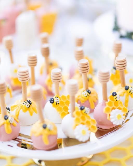 Pink and white cake pops with honeycomb and bee details on honey dipper sticks