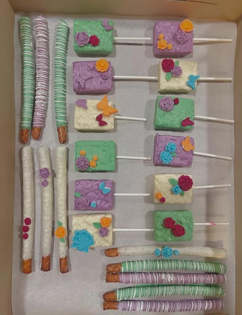 Pastel rice krispie pops and pretzel rods with sugar flowers and butterflies